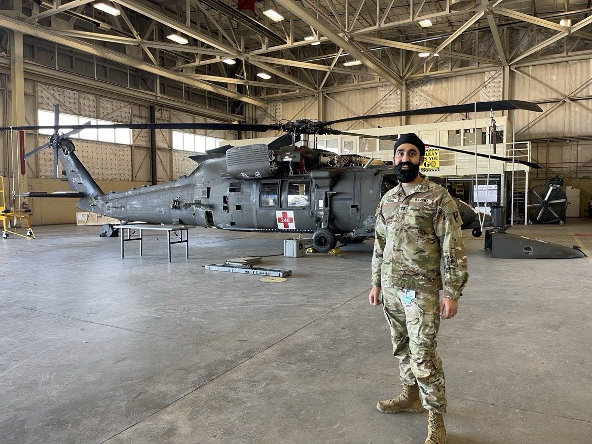 Dr. Grewal in U.S. Army uniform in front of a UH-60 medevac helicopter
